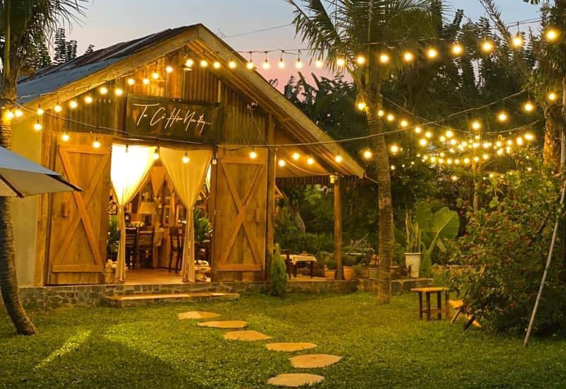 Quán cafe garden Pleiku ban đêm — nhà gỗ, đèn dây, vườn xanh, bậc đá
